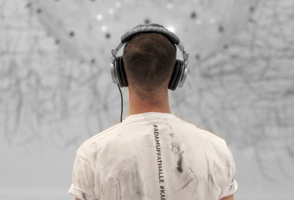 Visitor with headphones from behind with the interactive installation ADA in the background.
