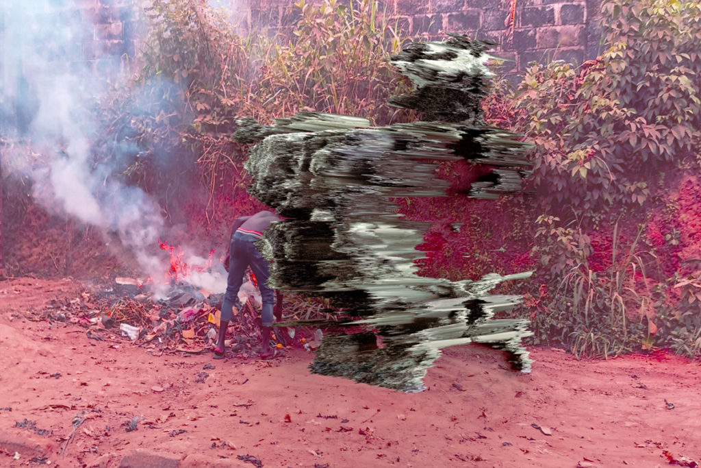 Digital sculpture from text disrupting photograph of a fire being tended on red clay earth.