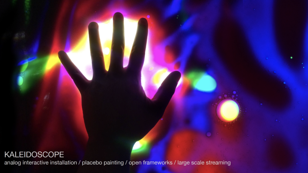 Shady hand from above on an illuminated vibrant colours background at interactive installation KALEIDOSCOPE.