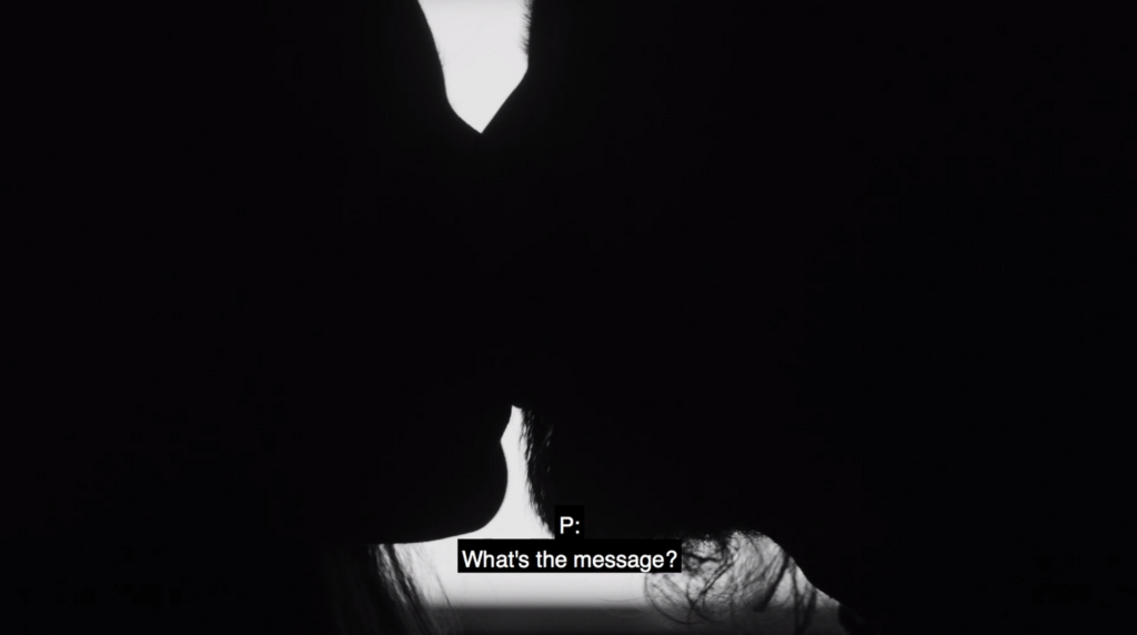 The silhouette of a man and a woman kissing in a close up in a black and white film image. The subtitles read: “What’s the message?”